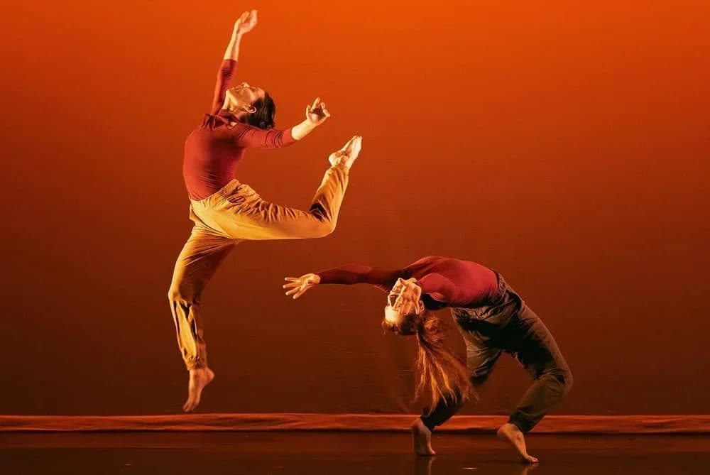 Two dancers against an orange backdrop